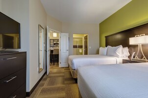 A hotel room with two beds, a TV, a desk, and a walk-in closet.