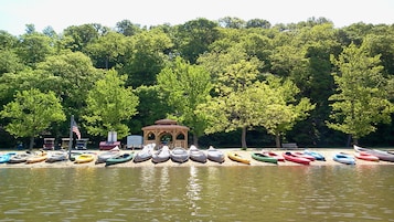 A lakeside setting with a gazebo and a row of canoes.