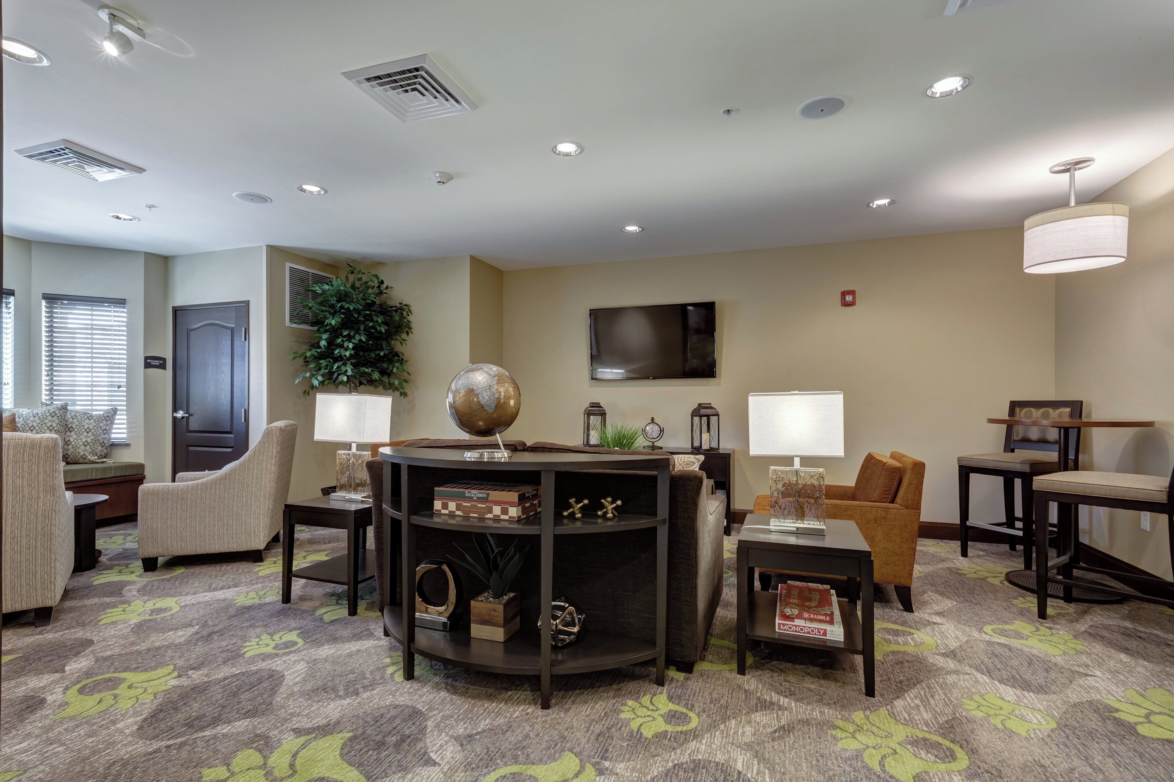 A hotel lobby with a seating area, a flat-screen TV mounted on the wall, and a globe on a table.