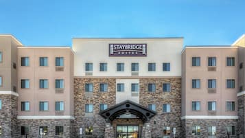 A Staybridge Suites hotel with a modern facade, multiple windows, and a prominent entrance.