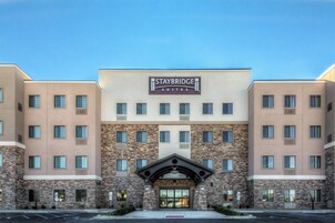 Un hotel Staybridge Suites con fachada moderna, múltiples ventanas y una entrada destacada.