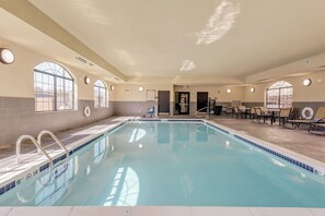 Una piscina con superficie de agua cristalina, rodeada de sillones de descanso y una zona de hamacas.