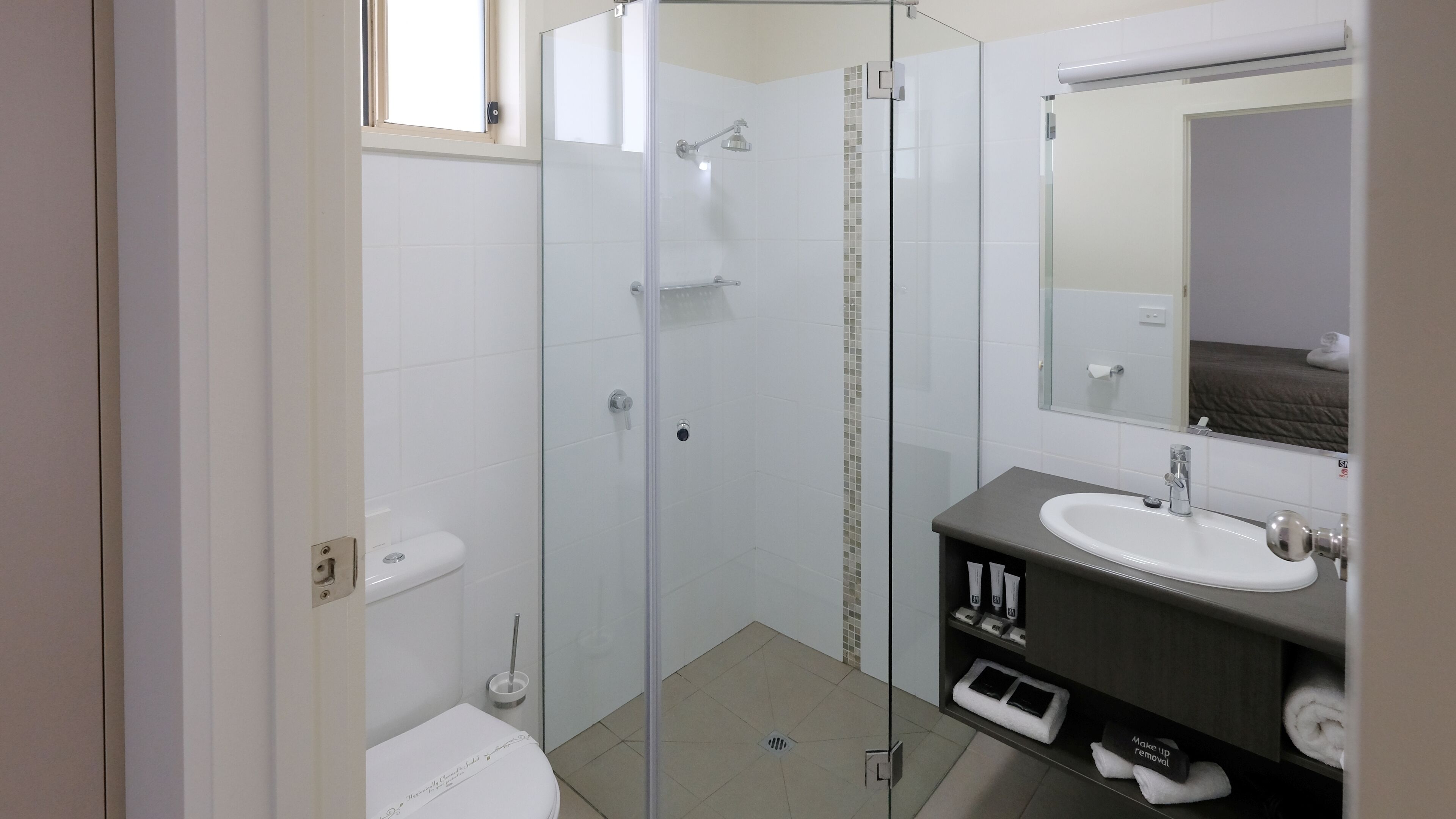 A modern bathroom with a glass-enclosed shower, a white sink, and a mirror above it.