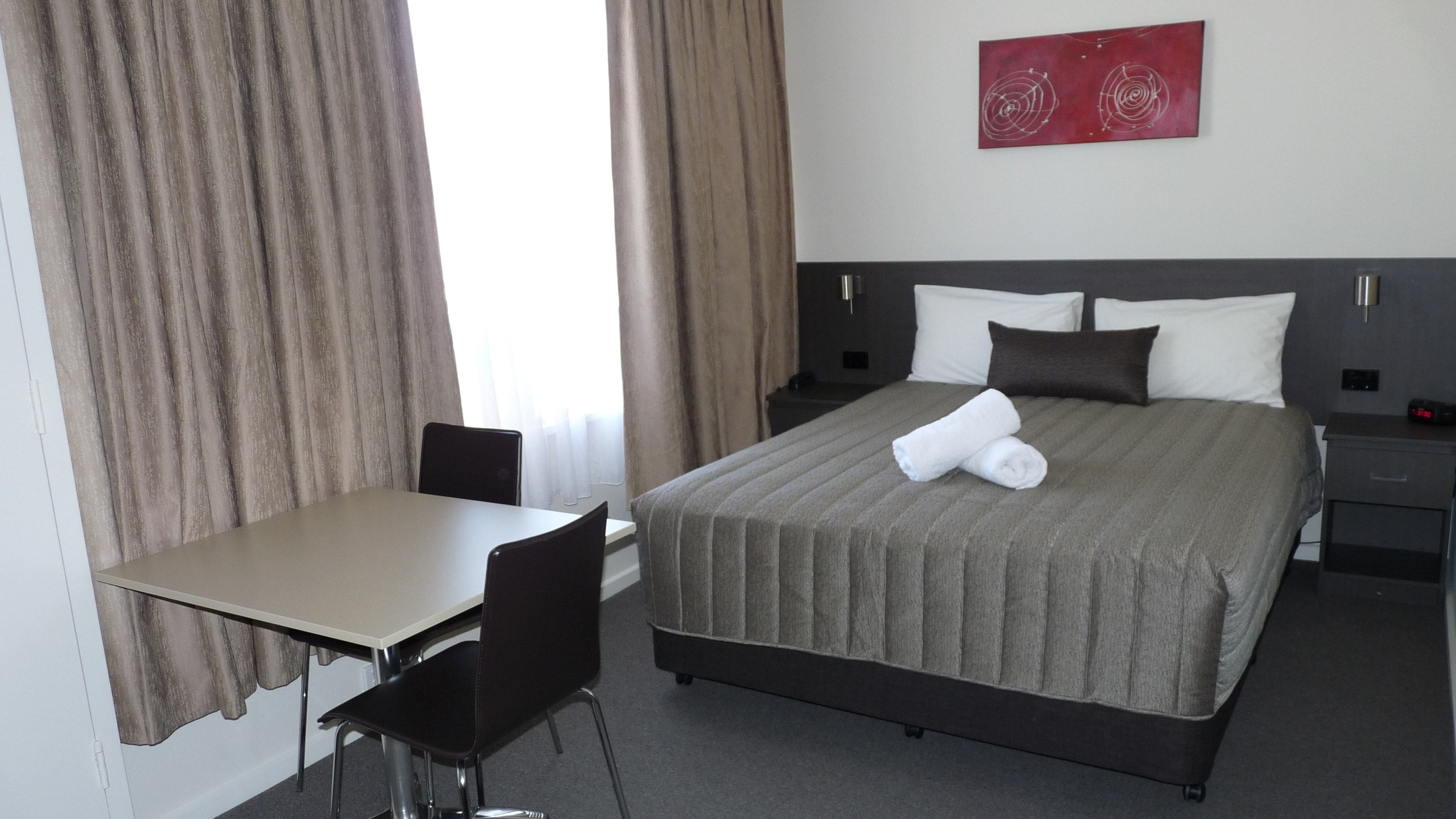 A hotel room with a bed, a desk, and a chair.