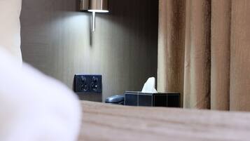 Una habitación de hotel con una mesita de noche, una lámpara y una caja de pañuelos.