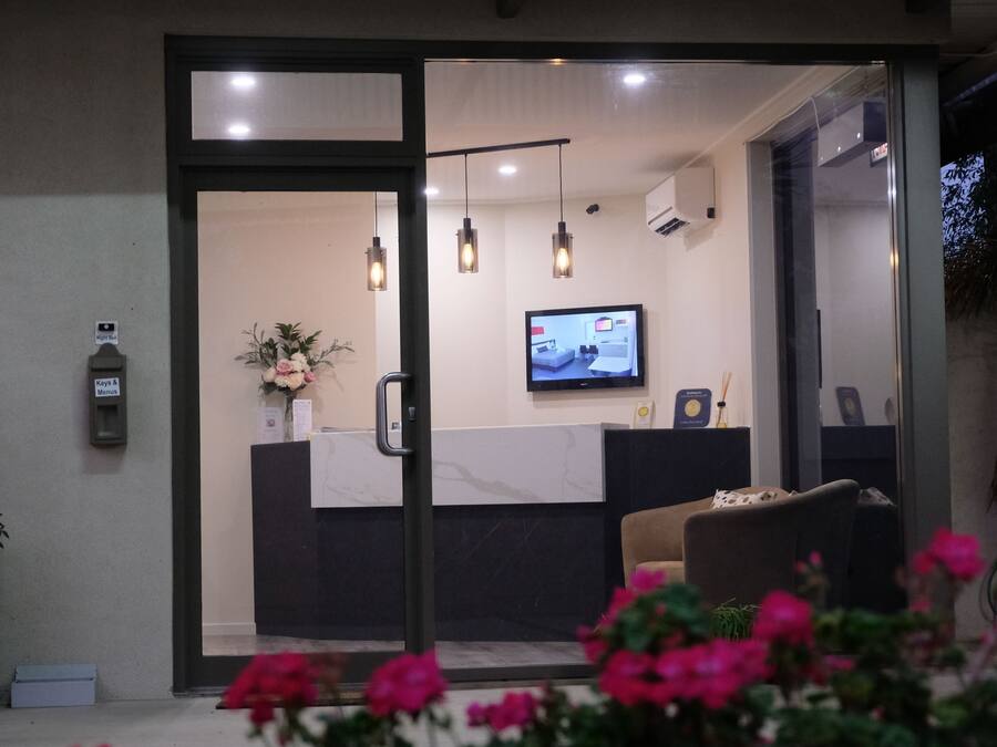 A reception area with a reception desk, a television screen, and a potted plant.
