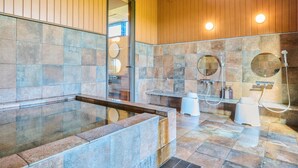 Un baño moderno con una bañera de hidromasaje con mampara de vidrio, zona de ducha con cabezal de ducha manual y tocador con espejo.