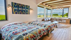 Un dormitorio con dos camas, un escritorio y vistas al exterior.