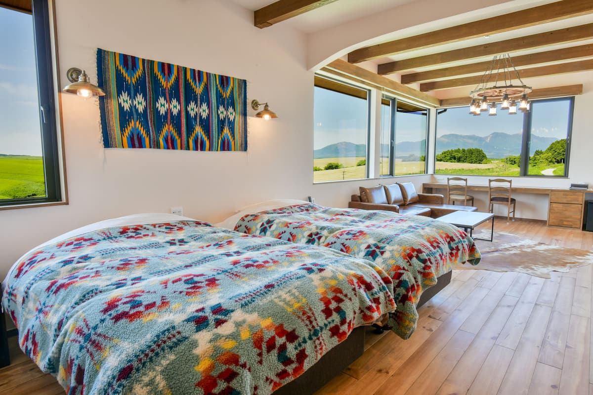 Un dormitorio con dos camas, un escritorio y vistas al exterior.