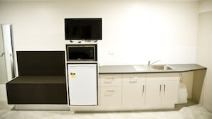 A compact kitchen with a microwave, refrigerator, and sink.