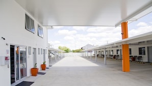 A spacious indoor area with a covered walkway, potted plants, and a clear view of the sky.