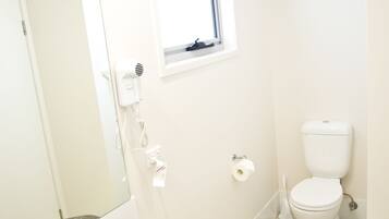 Un bagno con un lavandino bianco, uno specchio, una finestra e un water.
