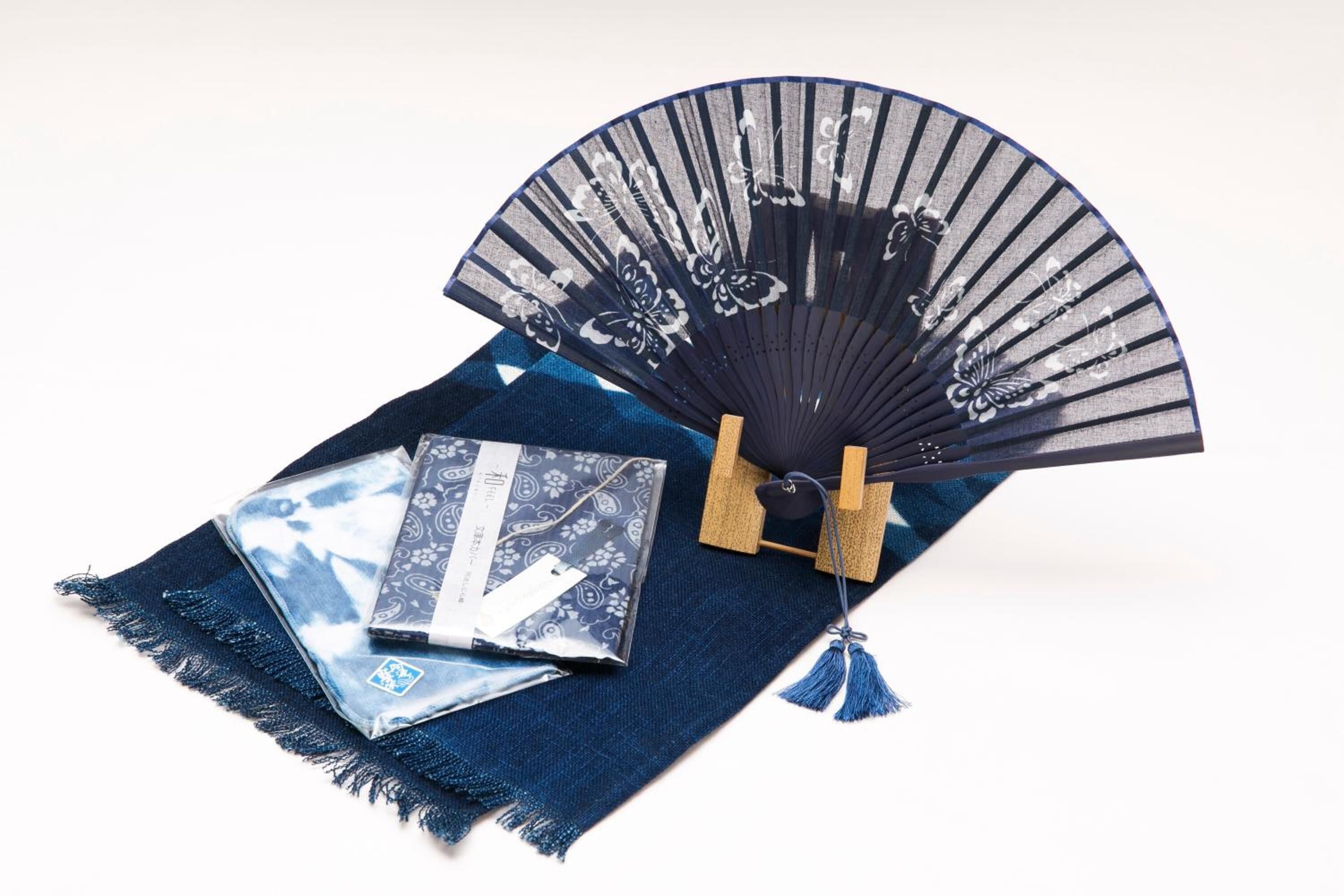 Un éventail bleu orné de motifs floraux, un tissu bleu et une carte sur un tissu bleu.