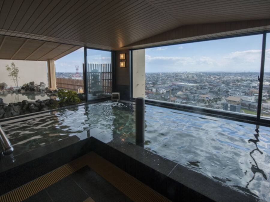 A modern indoor pool with a city view, large windows, and a wooden ceiling.