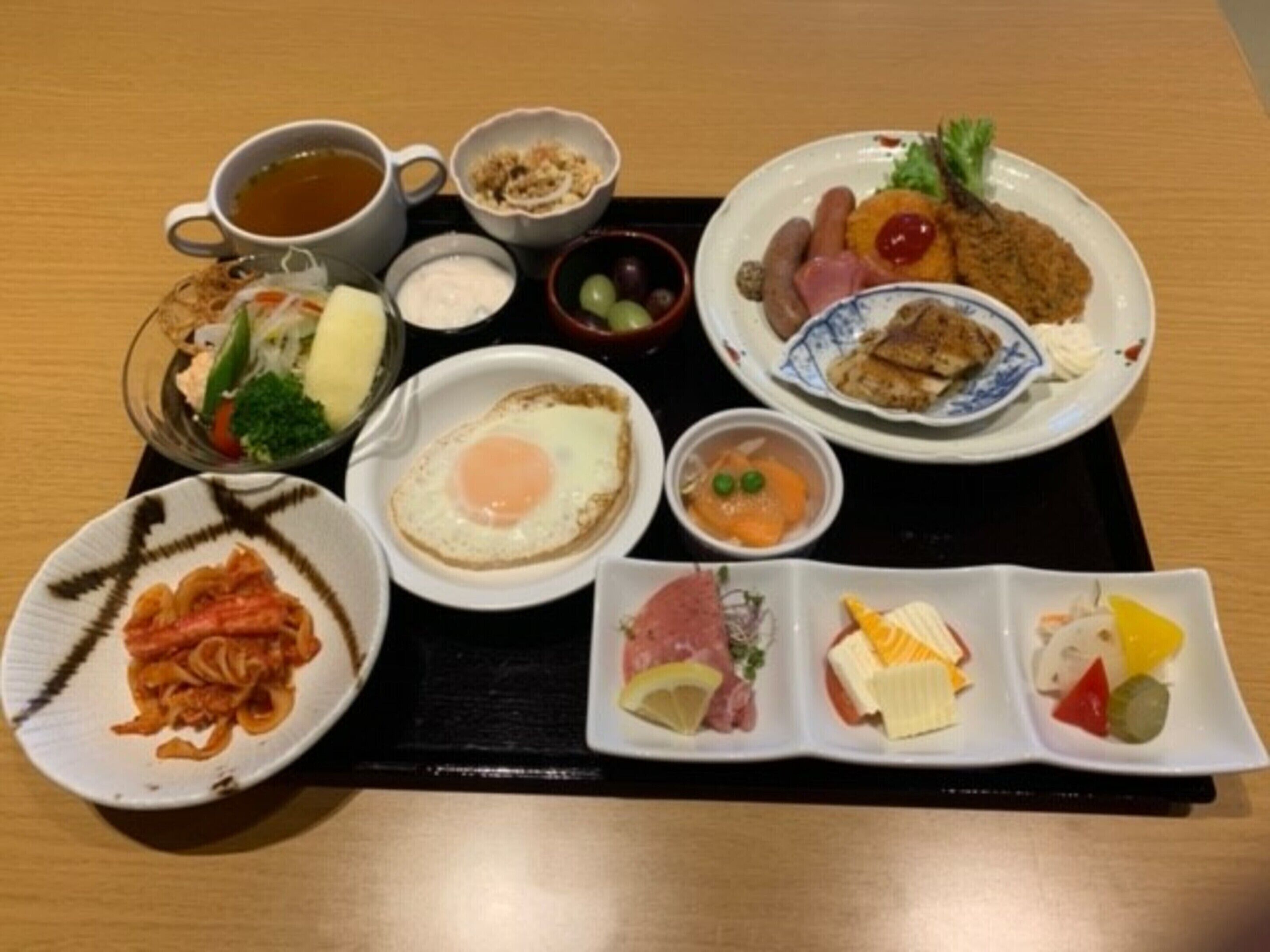 A tray with various breakfast items including eggs, sausages, and a cup of tea.