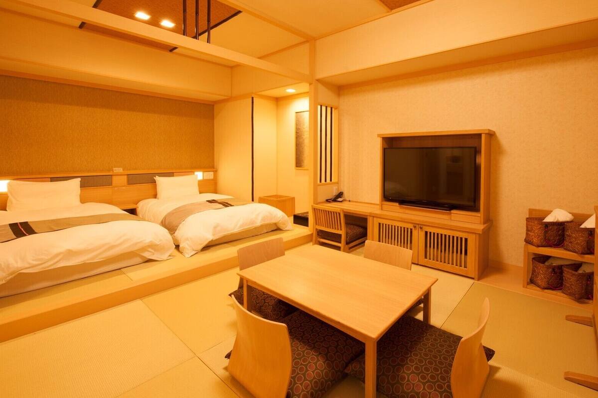 A hotel room with a bed, a TV, a desk, and a chair.
