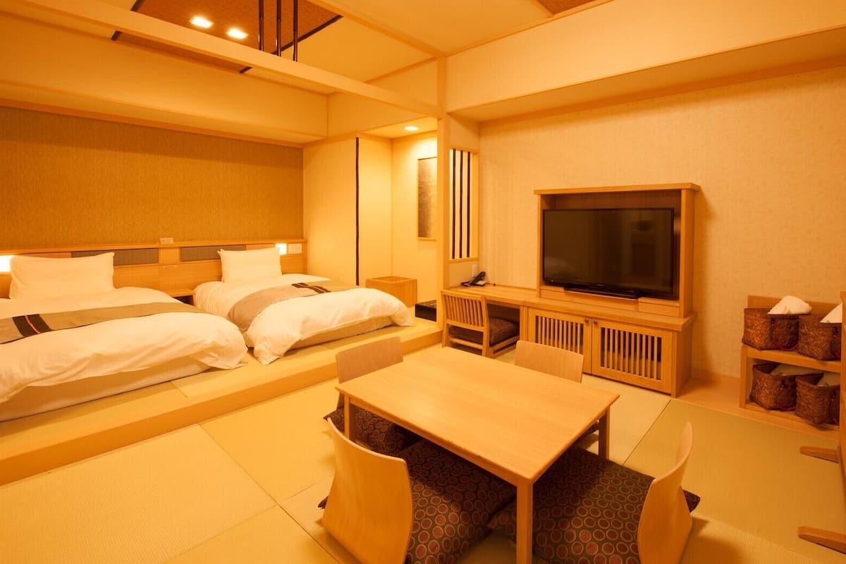 Ein Hotelzimmer mit Bett, Fernseher, Schreibtisch und Stuhl.