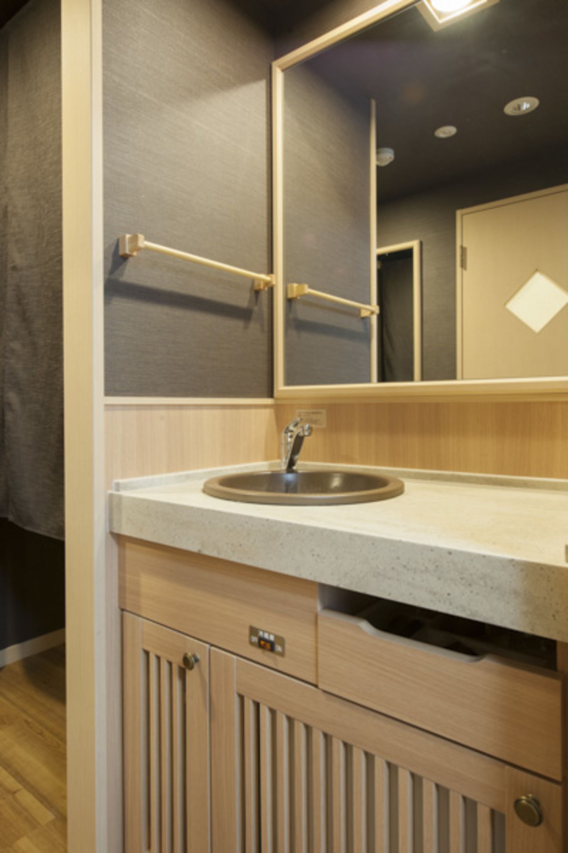 A bathroom with a sink, mirror, towel rack, and wooden cabinets.