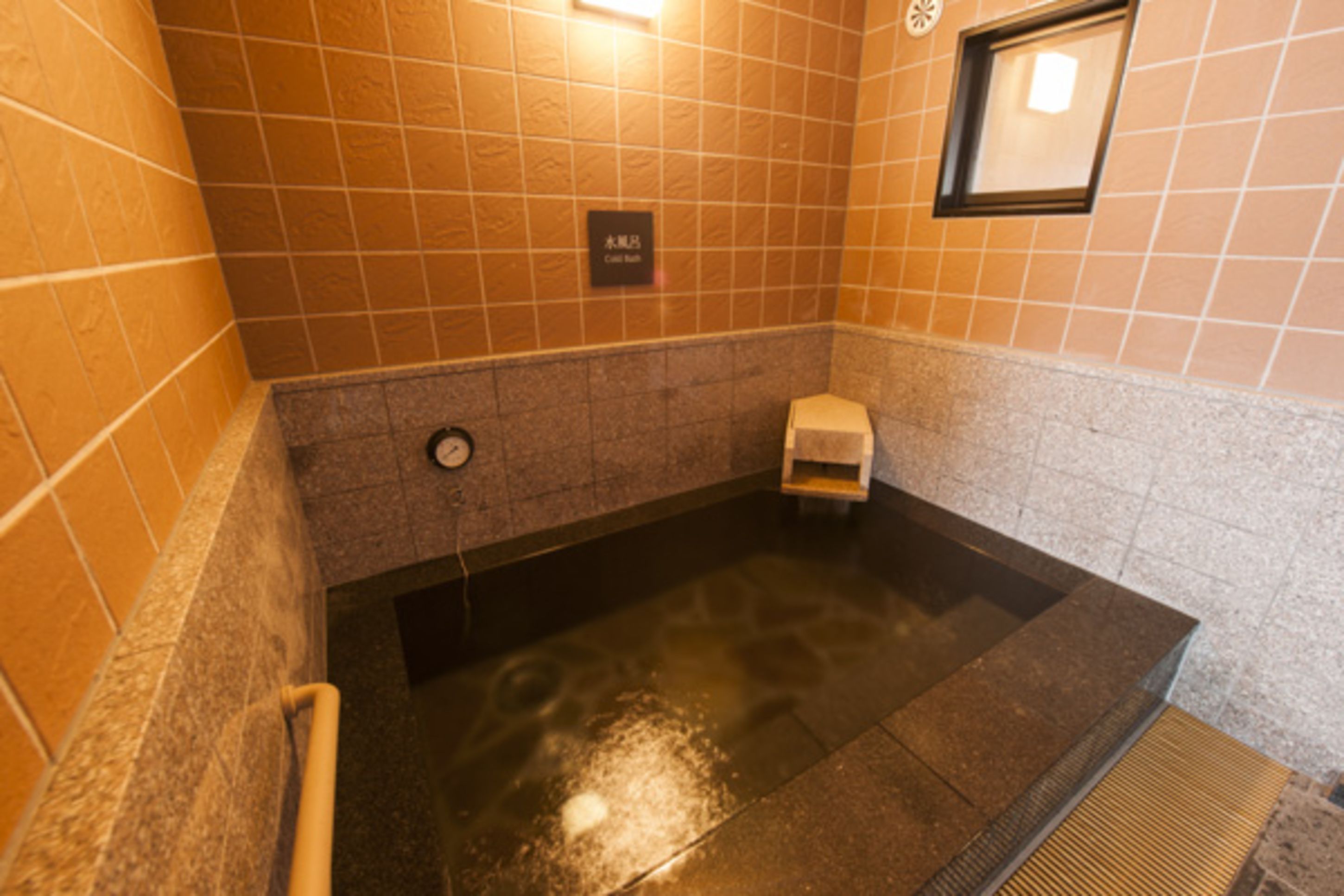 A hot tub area with tiled walls and a sign indicating a call button.