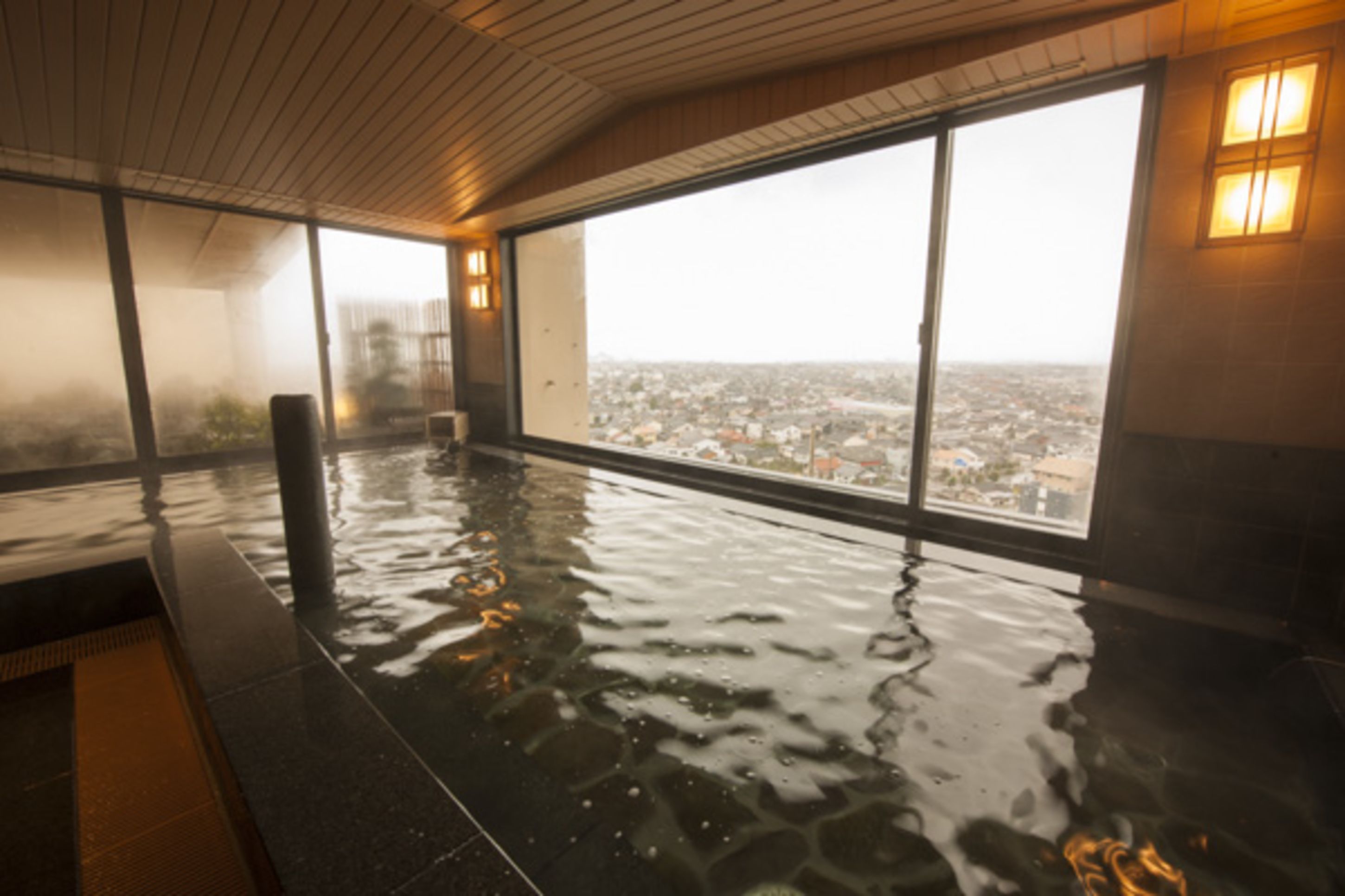 A large indoor swimming pool with a city view through large windows.