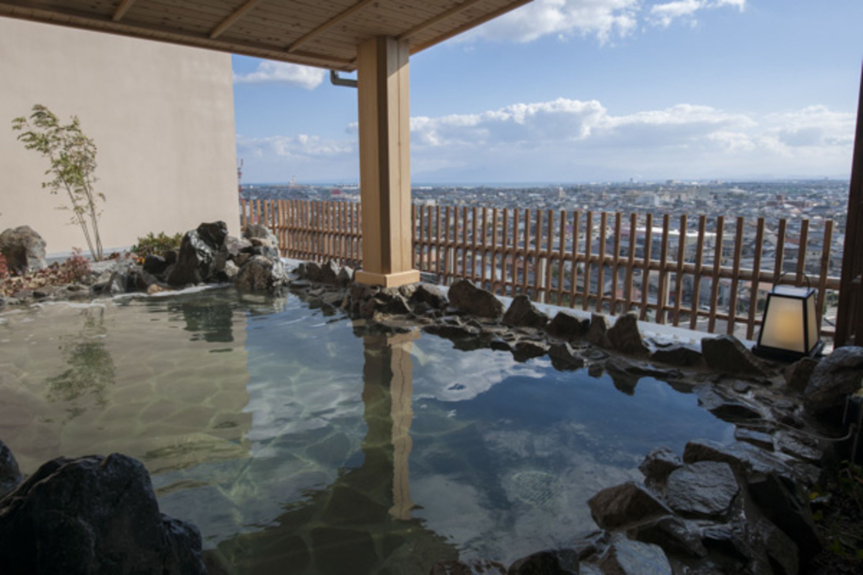 Een traditioneel Japans onsen met een houten hek en uitzicht op de stad.