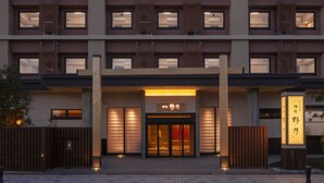 En moderne hotelindgang med en glasdør, et skilt med kinesiske tegn og et træhegn foran.