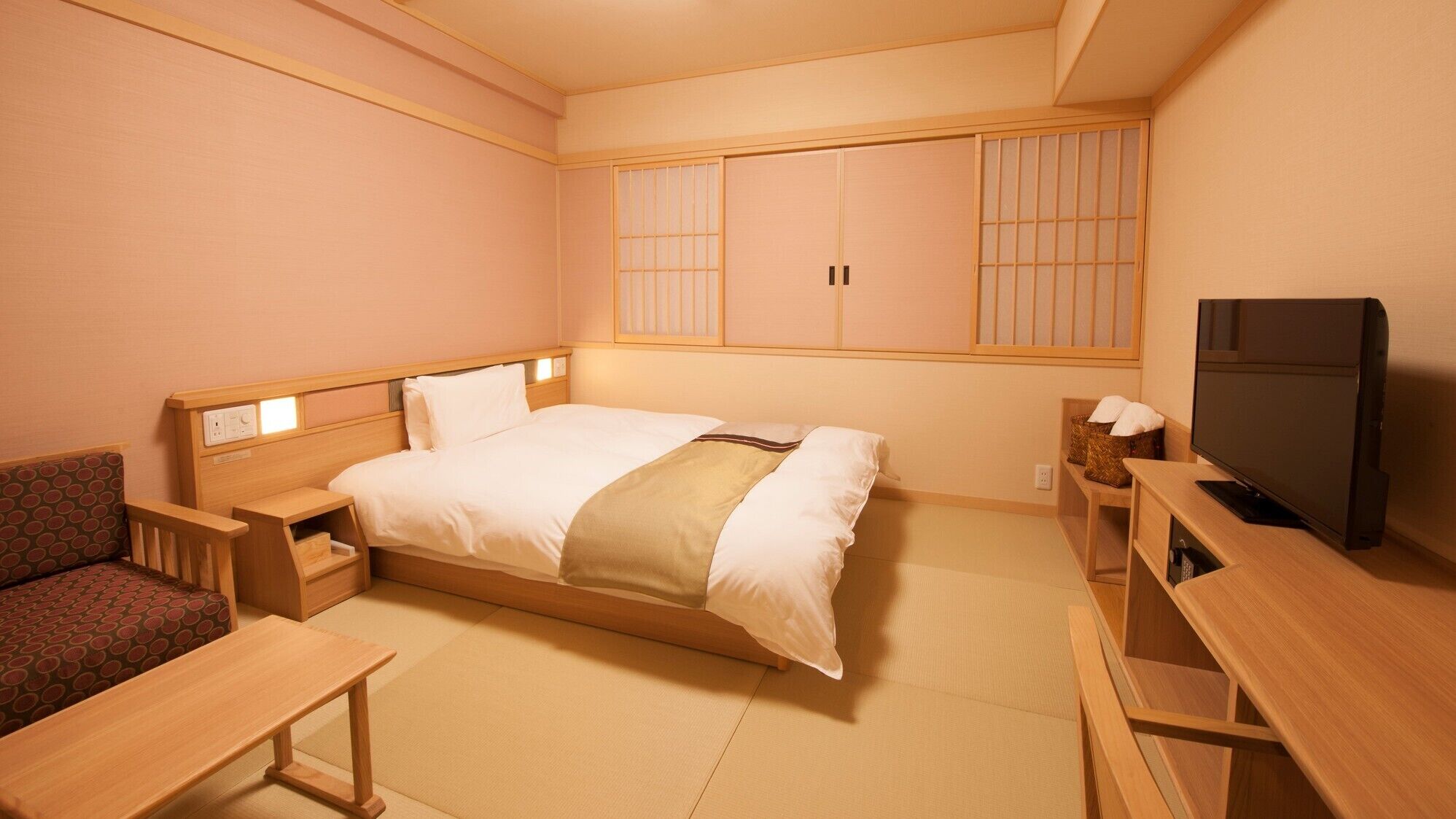 A hotel room with a bed, a TV, a desk, and a sofa.