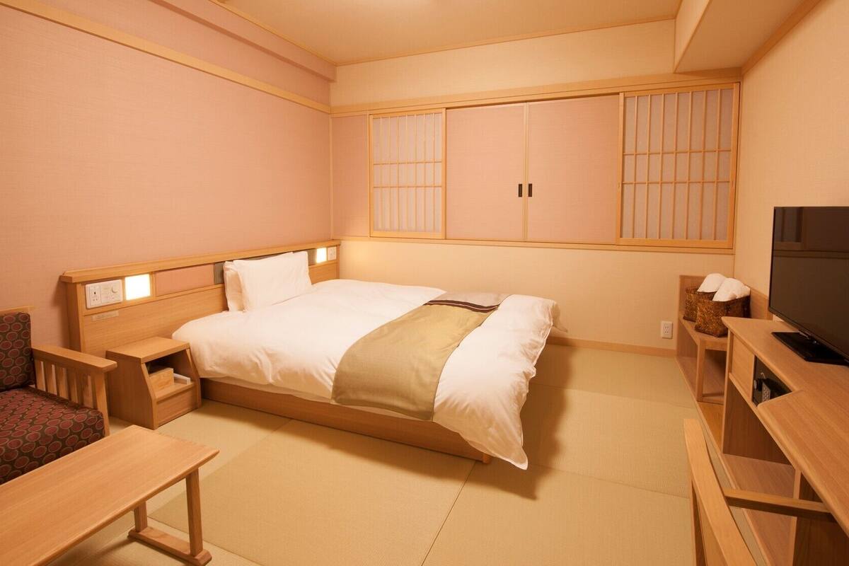 A hotel room with a bed, a TV, a desk, and a sofa.