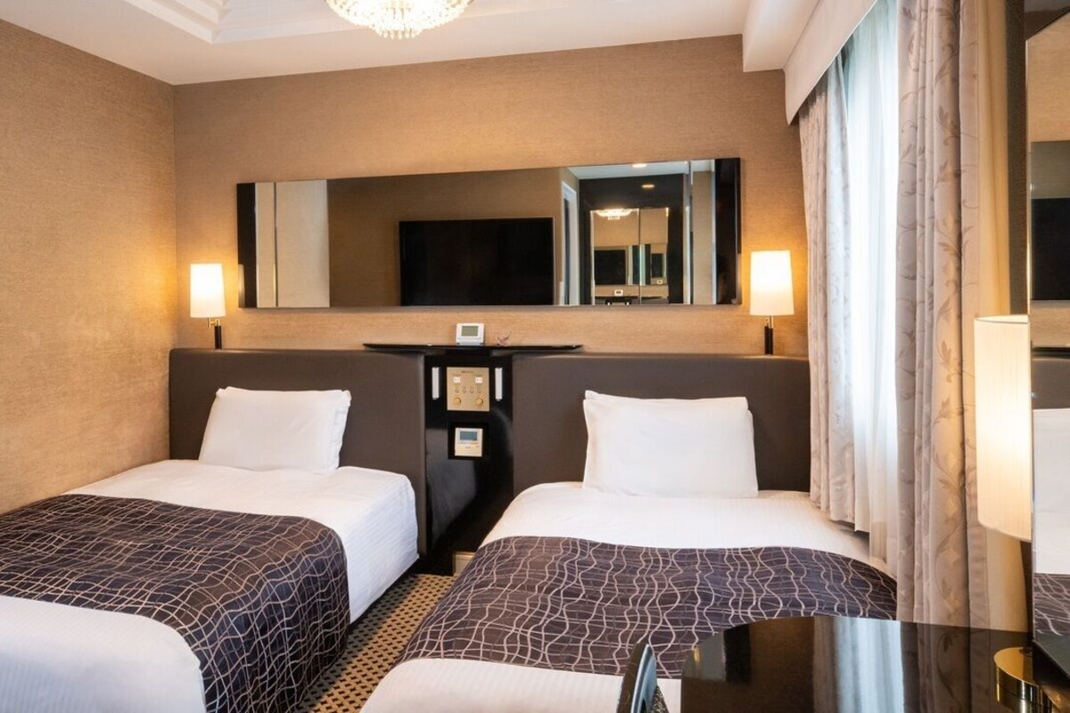 Een hotelkamer met twee bedden, een flatscreen televisie, een bureau en een spiegel.