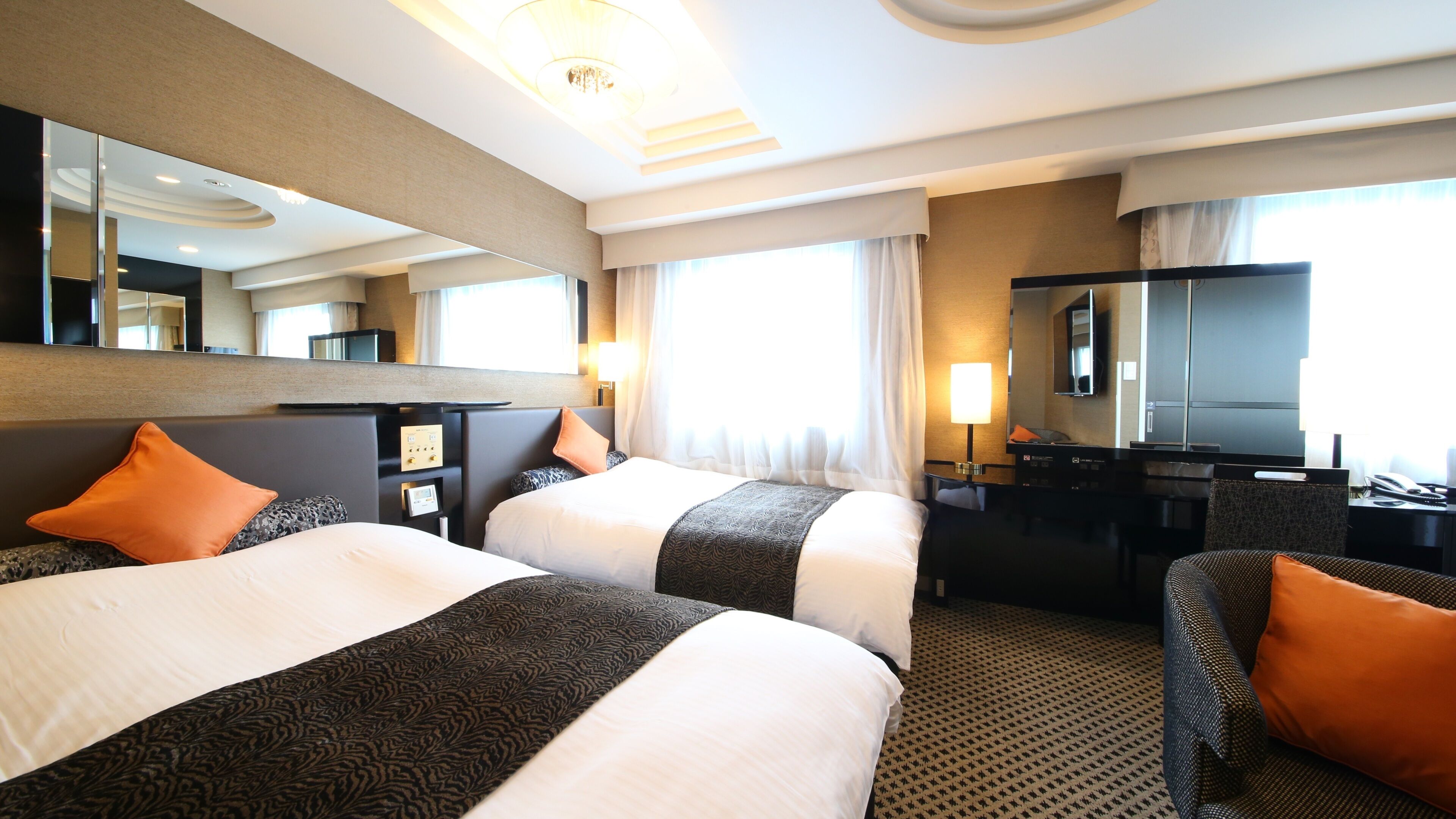 Een hotelkamer met twee bedden, een bureau, een stoel, een televisie en een grote spiegel.