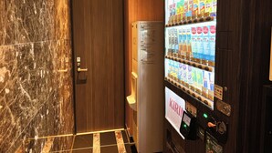 A vending machine with a Kirin logo, a door with a handle, and a marble wall. - APA Hotel Ueno Ekikita (Tokyo)