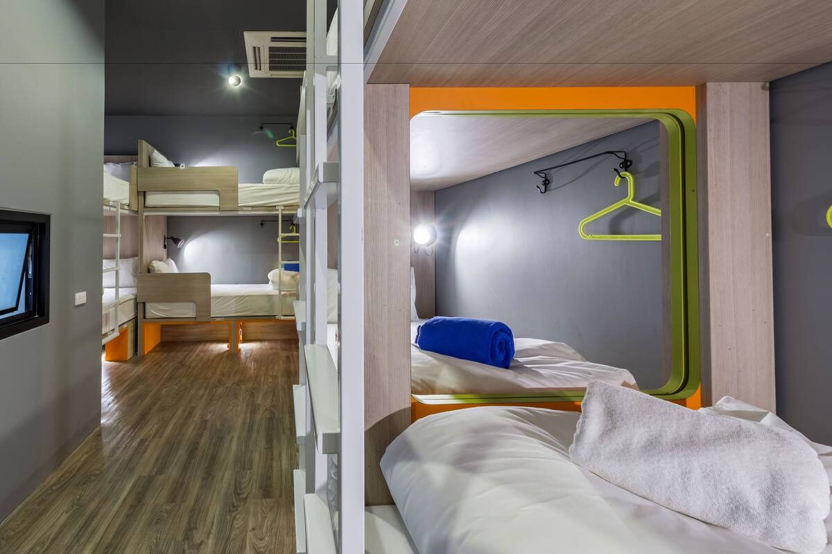 A modern hotel room with bunk beds, a mirror, and a hanging clothes rack.
