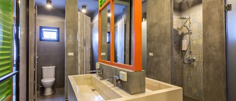 A modern bathroom with a large sink, a toilet, and a shower area.
