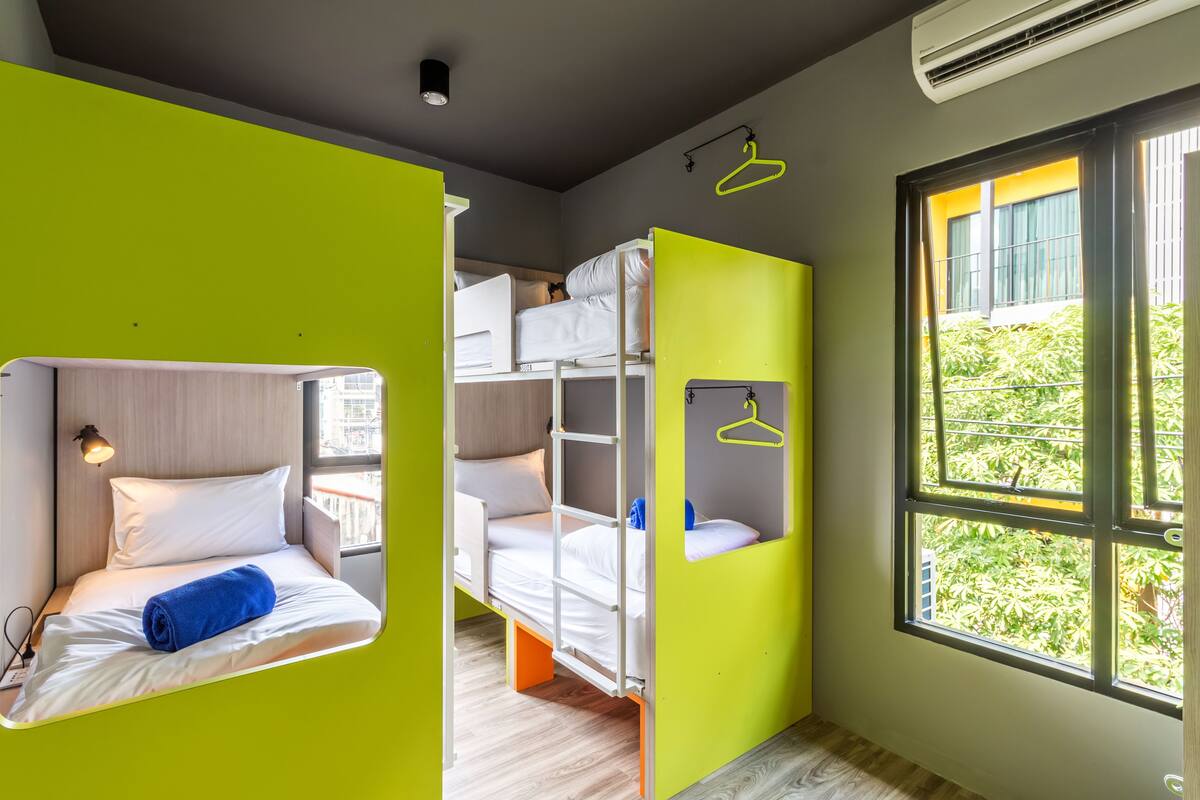 A compact room with bunk beds, a window with a view of greenery, and a bright green accent wall.