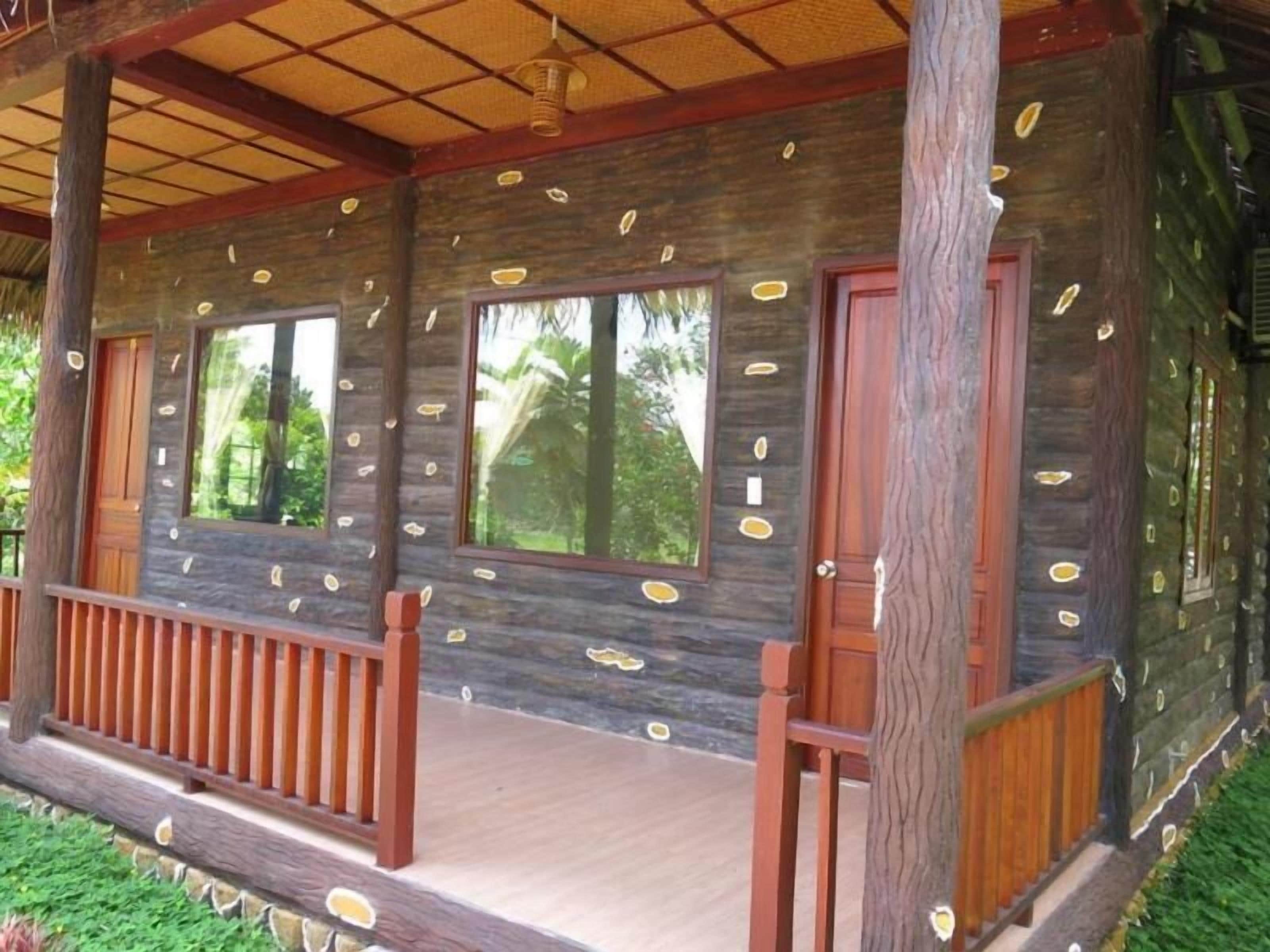Eine Holzhütte mit Veranda, großen Fenstern und einem Strohdach.
