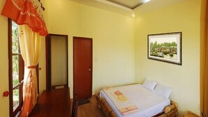 Una habitación con cama, escritorio, puerta y ventana con cortinas.