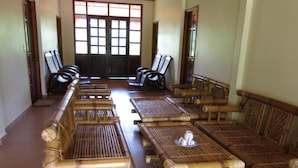 Una habitación con muebles de bambú organizados en filas, ventanas amplias con diseño de cuadrícula y suelo de madera.