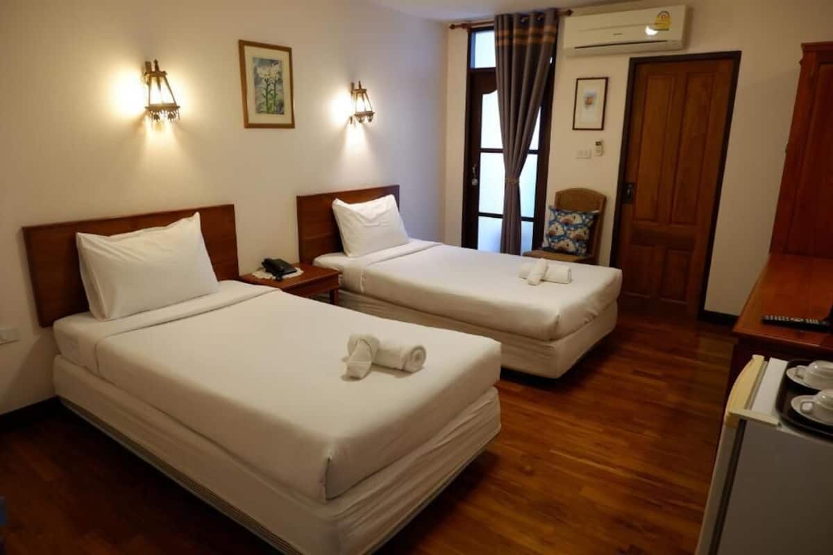 Une chambre d’hôtel avec deux lits, un plancher en bois, un bureau avec un téléphone et un appareil de climatisation.