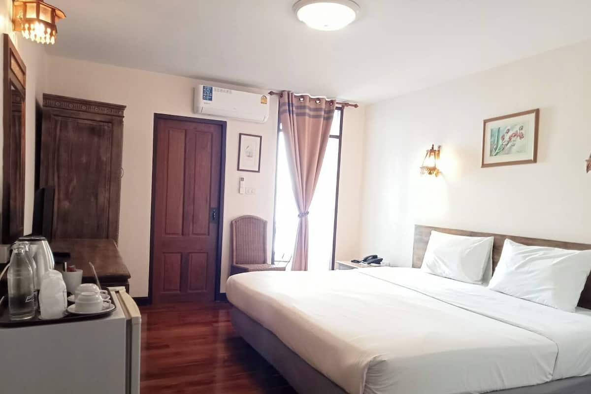 Une chambre d’hôtel comprenant un lit, un bureau avec un téléphone, une chaise, une armoire et un appareil de climatisation.