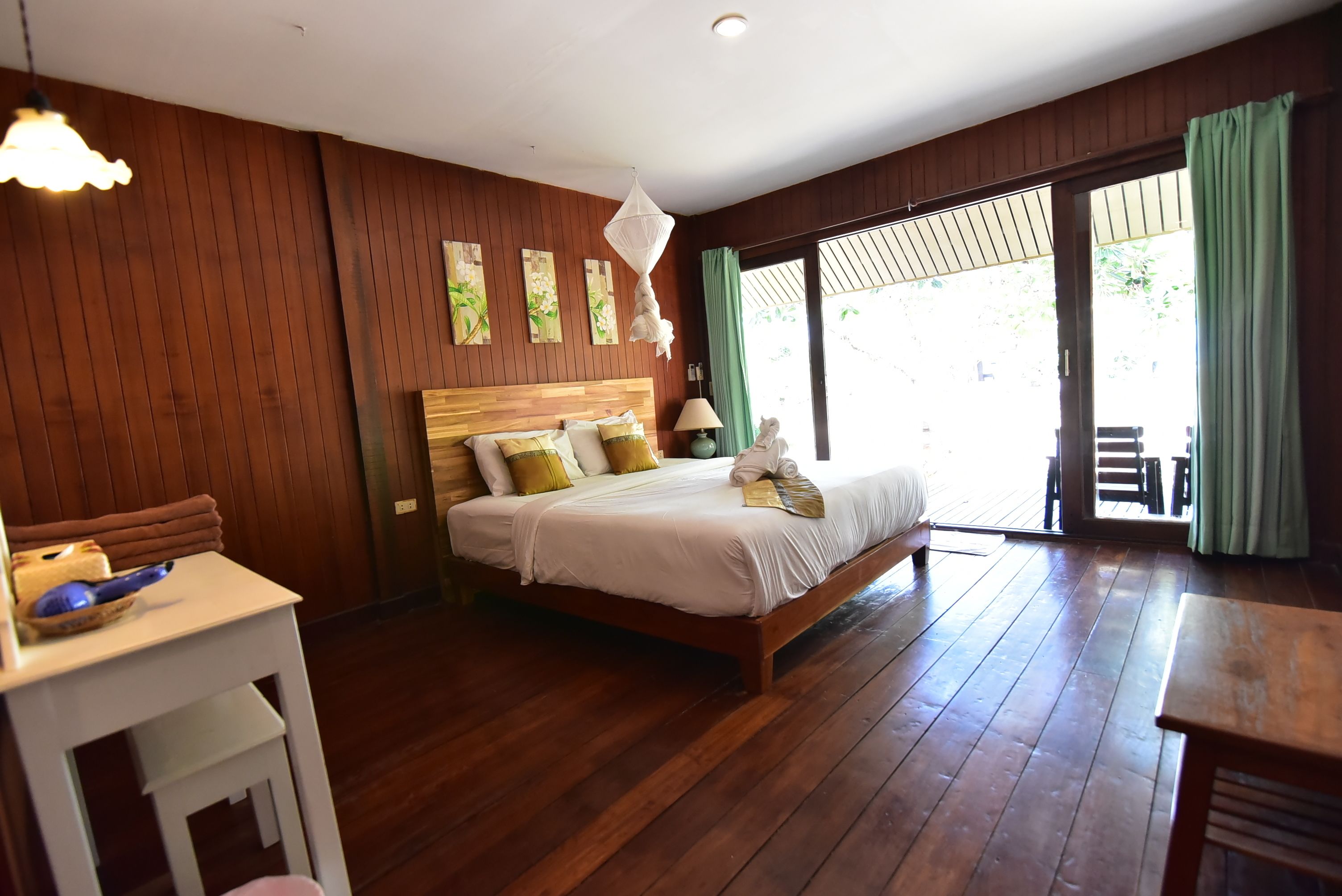 Un dormitorio con una cama de madera, una mesita de noche, una mesa con un bol y vistas al exterior a través de una puerta corredera.