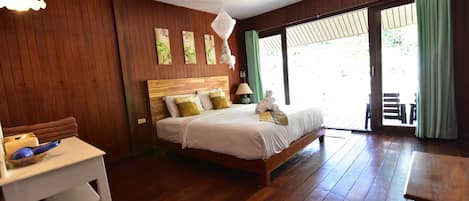Un dormitorio con una cama de madera, una mesita de noche, una mesa con un bol y vistas al exterior a través de una puerta corredera.