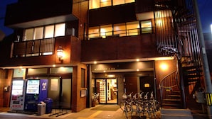A Seibido Inn with a brick facade, a visible entrance, vending machines, and bicycles parked outside. - Seibido Inn - Hostel (Kyoto)