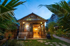 Un bâtiment rustique en bois, avec une enseigne indiquant « LAN AN GARDEN » et un petit espace porche.