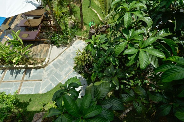 A lush garden with a stone pathway, a small pond, and a seating area with chairs and a table. - Lan Anh Garden Resort (Phu Quoc)