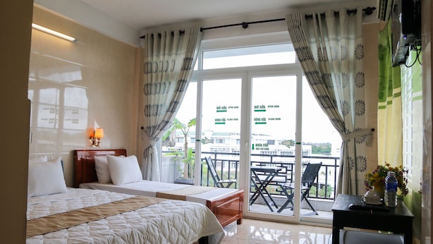 A hotel room with two beds, a balcony with a table and chairs, and a view of the cityscape.