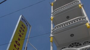 A hotel sign with contact information and a traditional multi-tiered building.