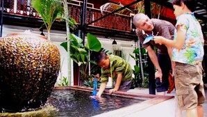 A man and a woman interacting with a water feature in a tropical setting. - Ganesha House (Chiang Mai)