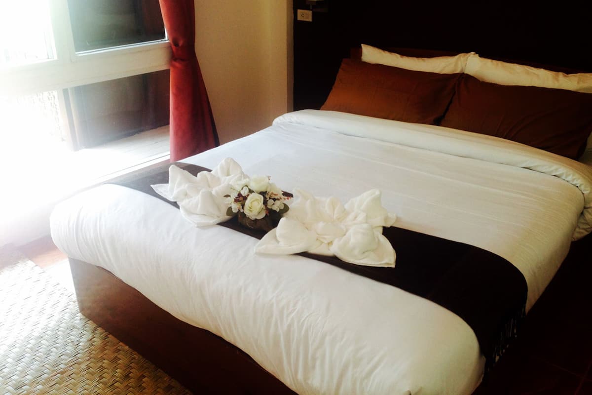 A neatly made bed with white linens and a decorative floral arrangement.