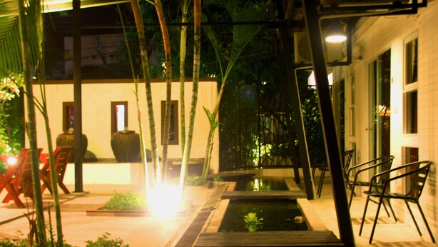 An outdoor patio area with a small water feature, seating, and potted plants. - Ganesha House (Chiang Mai)