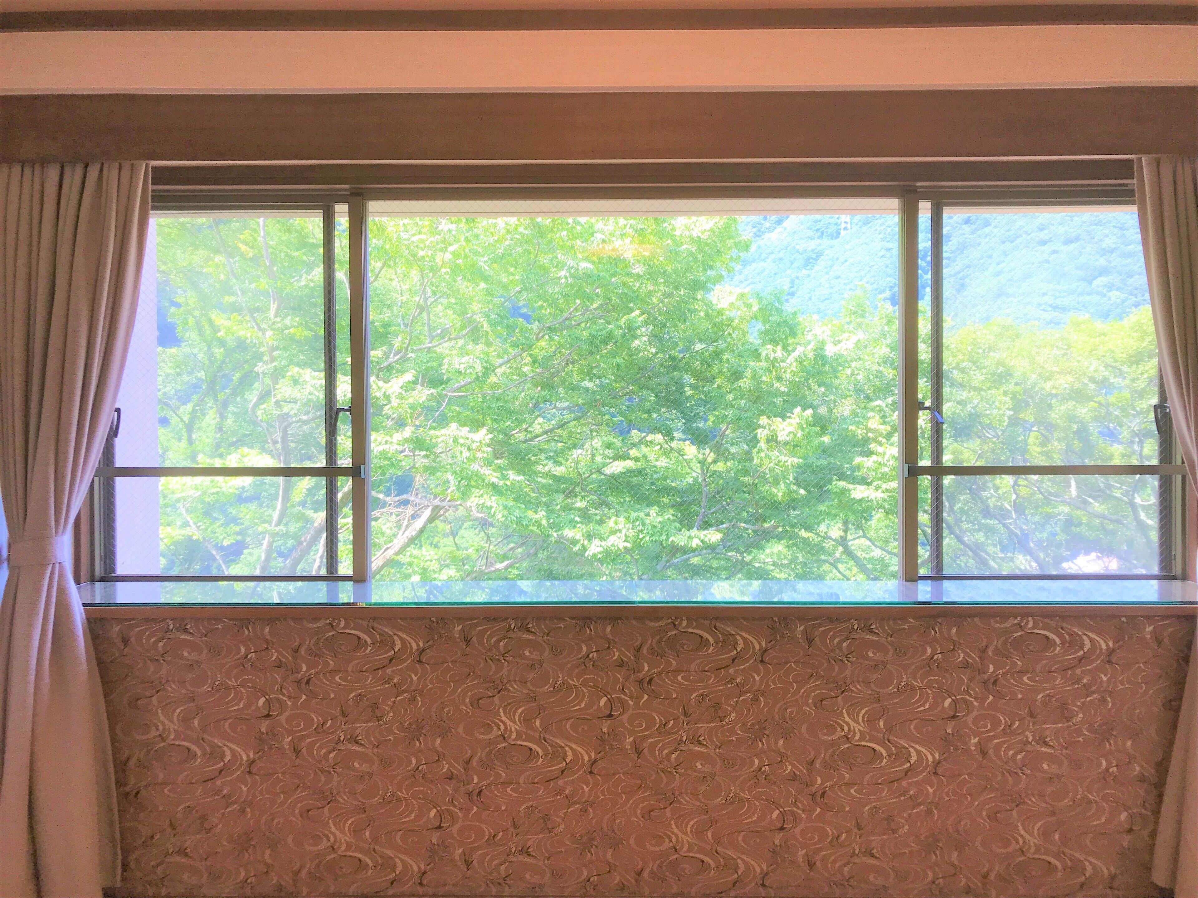 A room with a large window and a decorative wall panel.